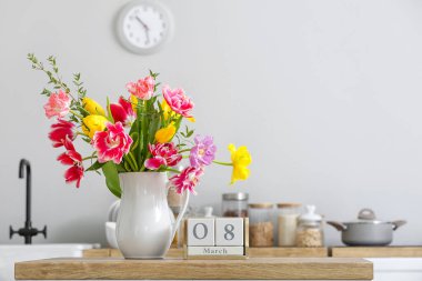 Güzel çiçekli sürahi ve mutfak tezgahında 8 Mart tarihli küp takvimi. Uluslararası Kadınlar Günü kutlamaları