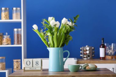 Çiçekli sürahi, kupa, badem kurabiyesi ve 8 Mart tarihli küp takvim mutfakta. Uluslararası Kadınlar Günü kutlamaları