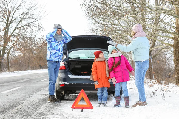 冬の雪の日に壊れた車の近くのストレスを受けた両親と彼らの子供 — ストック写真
