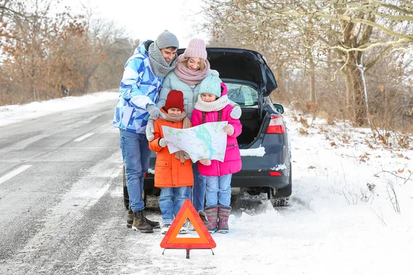 冬の雪の日に壊れた車の近くの地図を持つ両親とその小さな子供 — ストック写真