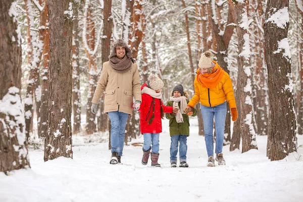 雪の冬の日に森の中を歩く幸せな家族 — ストック写真