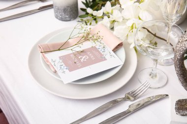 Düğün davetiyesi ve çigila çiçekleri olan şık bir masa.