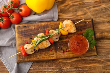 Ahşap arka planda sebzeli ızgara tavuk şişi ve sos.