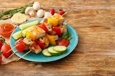 Ahşap arka planda sebzeli ızgara tavuk şişi.