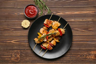 Ahşap arka planda sebzeli ızgara tavuk şişi ve sos.