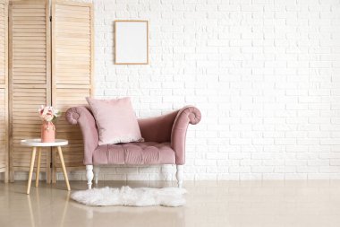 Şık bir kanepe, çiçekli vazo ve beyaz tuğla duvarın yanında katlanır ekran.