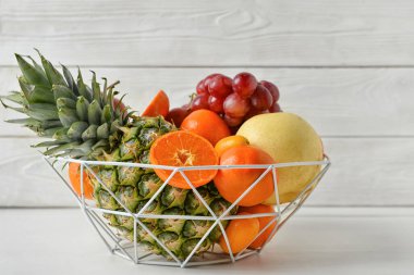 Beyaz ahşap arka planda sulu meyveler bulunan sepet.