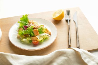Beyaz arka planda bir tabak lezzetli vegan Sezar salatası.