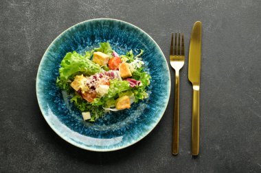 Siyah arka planda bir tabak lezzetli vegan Sezar salatası.