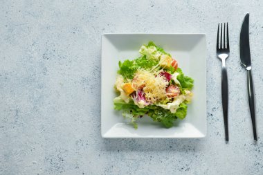 Hafif arka planda bir tabak lezzetli vegan Sezar salatası.