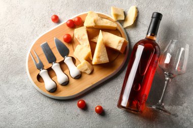 Lezzetli parmesan peyniri ve gri arka planda bir şişe şarapla ahşap tahta tahta.