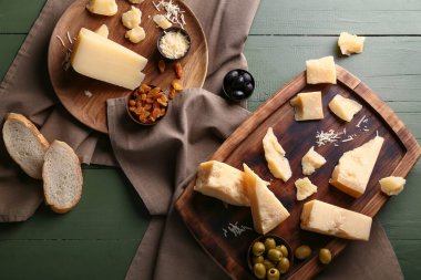 Yeşil ahşap arka planda lezzetli parmesan peyniri parçaları olan tabak ve yemek.