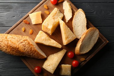 Lezzetli parmesan peyniri ve siyah ahşap arka planda ekmek parçaları olan tahta.