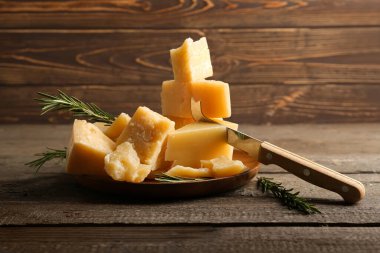 Ahşap zemin üzerinde lezzetli parmesan peyniri parçaları olan tabak.