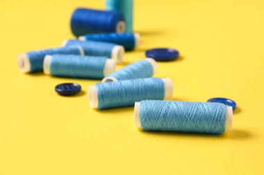 Sarı arkaplanda iplik makaraları ve düğmeler