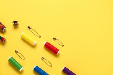 Sarı arkaplanda iplik makaraları ve iğneler