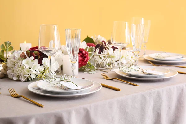 黄色の壁の近くに結婚式の招待状とジプシーの花とスタイリッシュなテーブル設定 — ストック写真