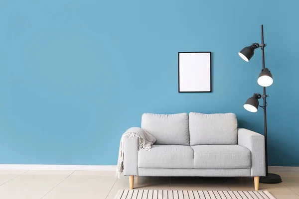 Stylish sofa and lamp near blue wall