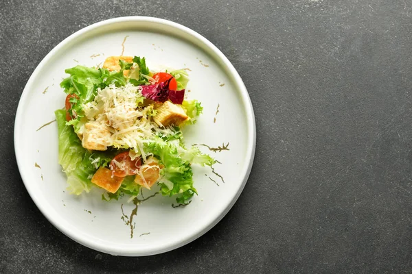 Plate of tasty vegan Caesar salad on black background