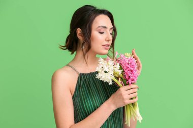 Yeşil arka planda sümbül çiçekleri olan güzel genç bir kadın.