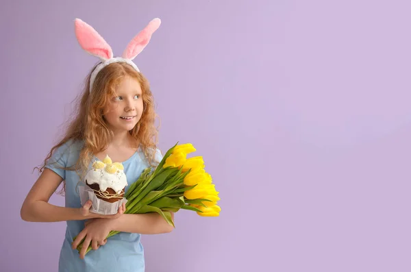 面白い女の子とともにウサギの耳 花とイースターケーキ上の色の背景 — ストック写真