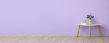 Üzerinde güzel sümbül çiçekleri olan vazo, yazı için yeri olan leylak duvarın yanındaki masada.