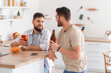 Bira ve patates kızartmalı erkek arkadaşlar mutfaktaki masada oturuyor.