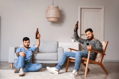 Evde bira şişeleriyle televizyon izleyen erkek arkadaşlar.