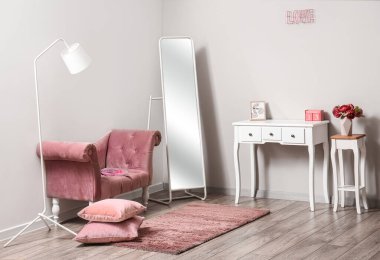 Pembe koltuklu, aynalı ve masalı şık bir oda.