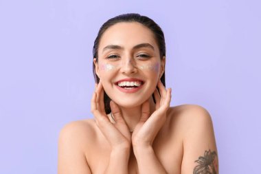 Yaratıcı makyajlı, gülümseyen kadın renk arkaplanına dokunuyor