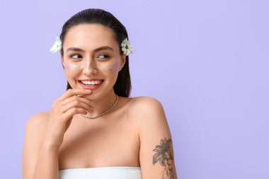 Yaratıcı makyajı ve papatya çiçekleri olan güzel bir kadın renk arka planına bakıyor.