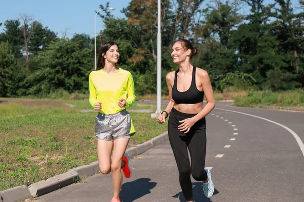 Sportif genç kadınlar dışarıda koşuyor.