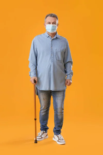 头戴医疗面罩 头戴黄底手杖的老年人 — 图库照片