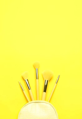 Sarı arkaplanda makyaj fırçaları olan kompozisyon
