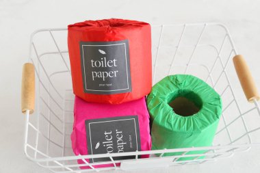 Beyaz arka planda tuvalet kağıdı ruloları olan sepet, yakın plan.