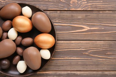Ahşap arka planda farklı çikolatalı Paskalya yumurtaları.