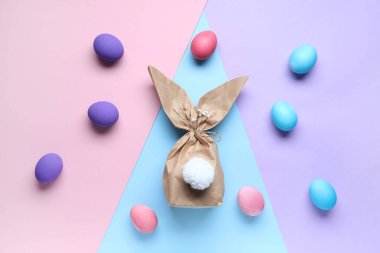 Renkli arkaplanda Paskalya tavşanı hediye paketi ve yumurta kompozisyonu