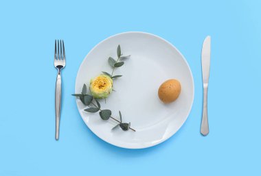 Paskalya yumurtası, şakayık çiçeği ve mavi arka planda okaliptüs dalları olan masa ayarı