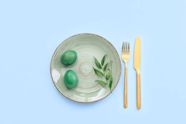 Mavi arka planda Paskalya yumurtası ve bitki dalı olan masa ayarı