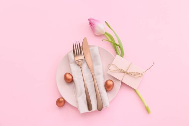 Paskalya yumurtaları ve pembe arka planda lale ile güzel bir masa.