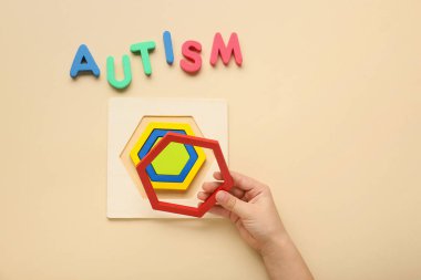 Bej arka planda oyuncak ve kelime AUTISM ile çocuk