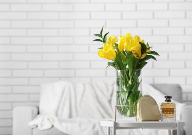 Sarı laleli vazo ve parfüm oturma odasında.