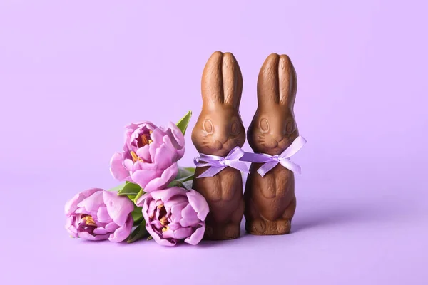 复活节巧克力兔子和紫丁香背景上美丽的郁金香花 — 图库照片