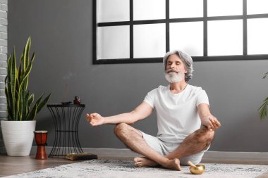 Olgun adam evde meditasyon yapıyor.