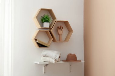 Raflarda süveter, şapka ve dekor yığını asılı.