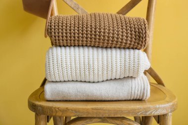 Tahta sandalye, kazak yığını ve sarı duvarın yanında şapka, yakın plan.