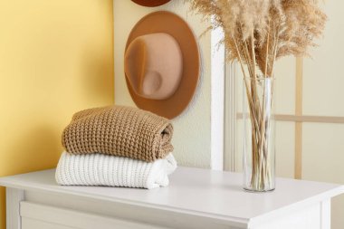 Koridordaki rafta sıcak süveter ve vazo yığını.