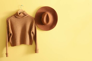 Sıcak süveter ve sarı duvarda asılı şık şapka.