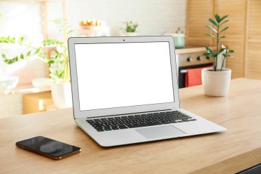 Modern dizüstü bilgisayar ve cep telefonu ışık odasındaki ahşap masada.