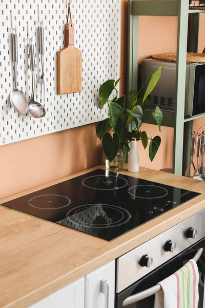 桌上的现代电炉和彩墙上装有厨房用具的踏板 — 图库照片